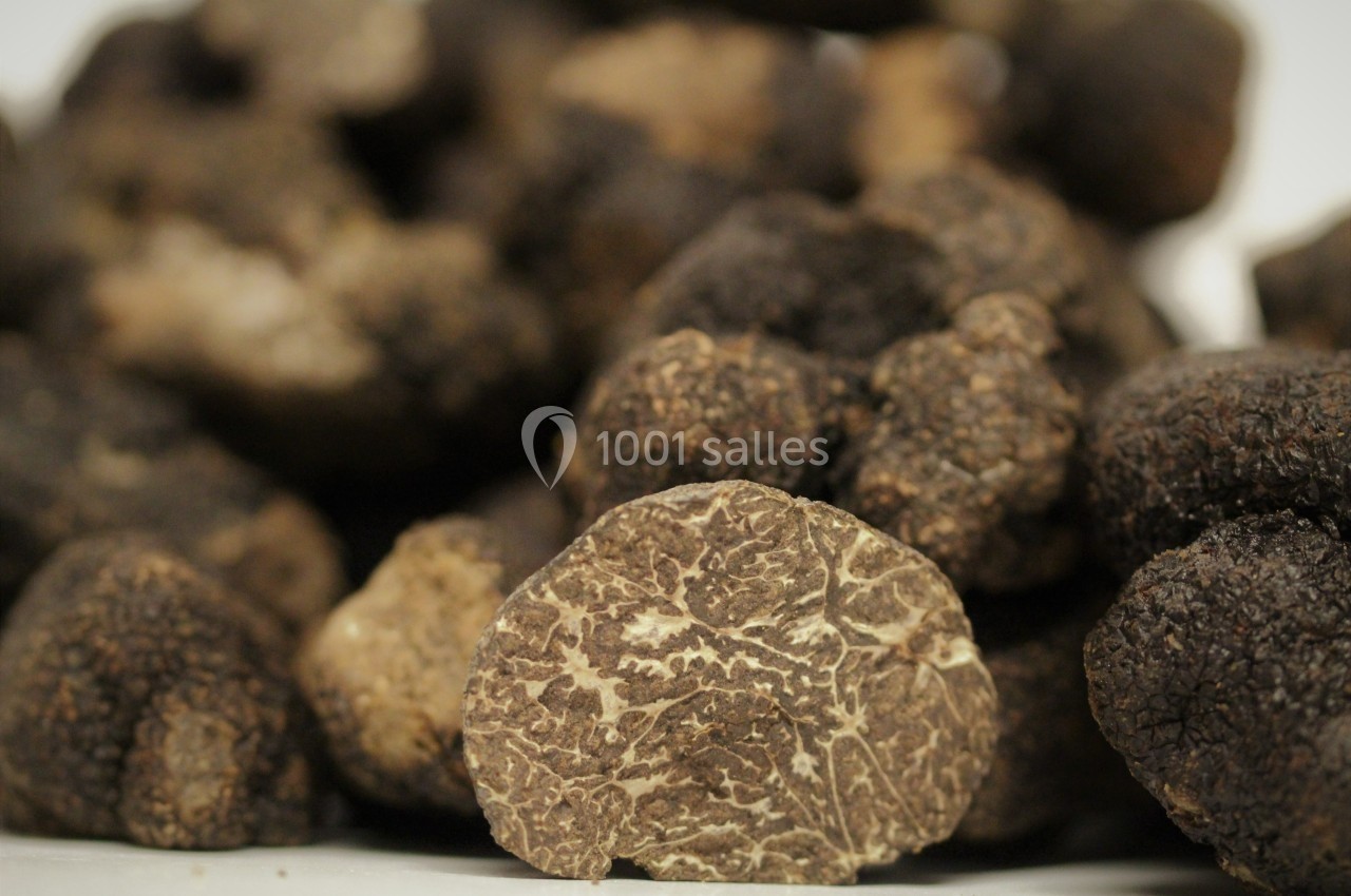 Truffes noires entières et une truffe coupée en gros plan, révélant son intérieur veiné.