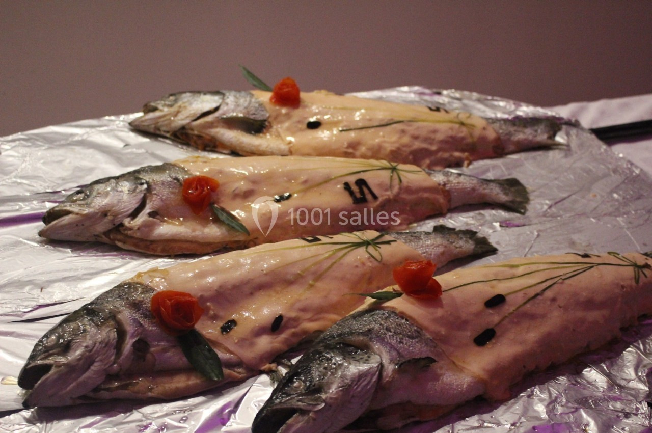 Quatre poissons entiers préparés pour la cuisson, garnis de pâte, herbes et décorations, disposés sur une feuille d…