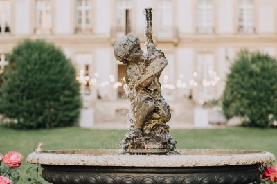 Manoir ancien entouré d'arbres et de buissons sous la neige, éclairé par une lumière hivernale douce.