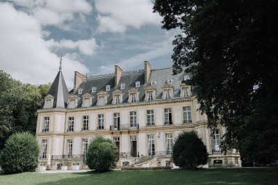 Manoir ancien entouré d'arbres et de buissons sous la neige, éclairé par une lumière hivernale douce.