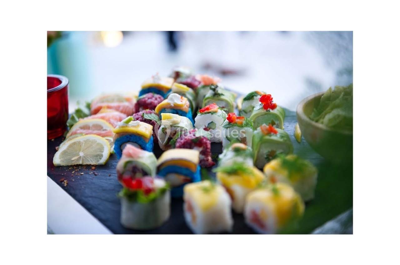 Assortiment de sushis colorés et variés présentés sur une ardoise, accompagné de tranches de citron.