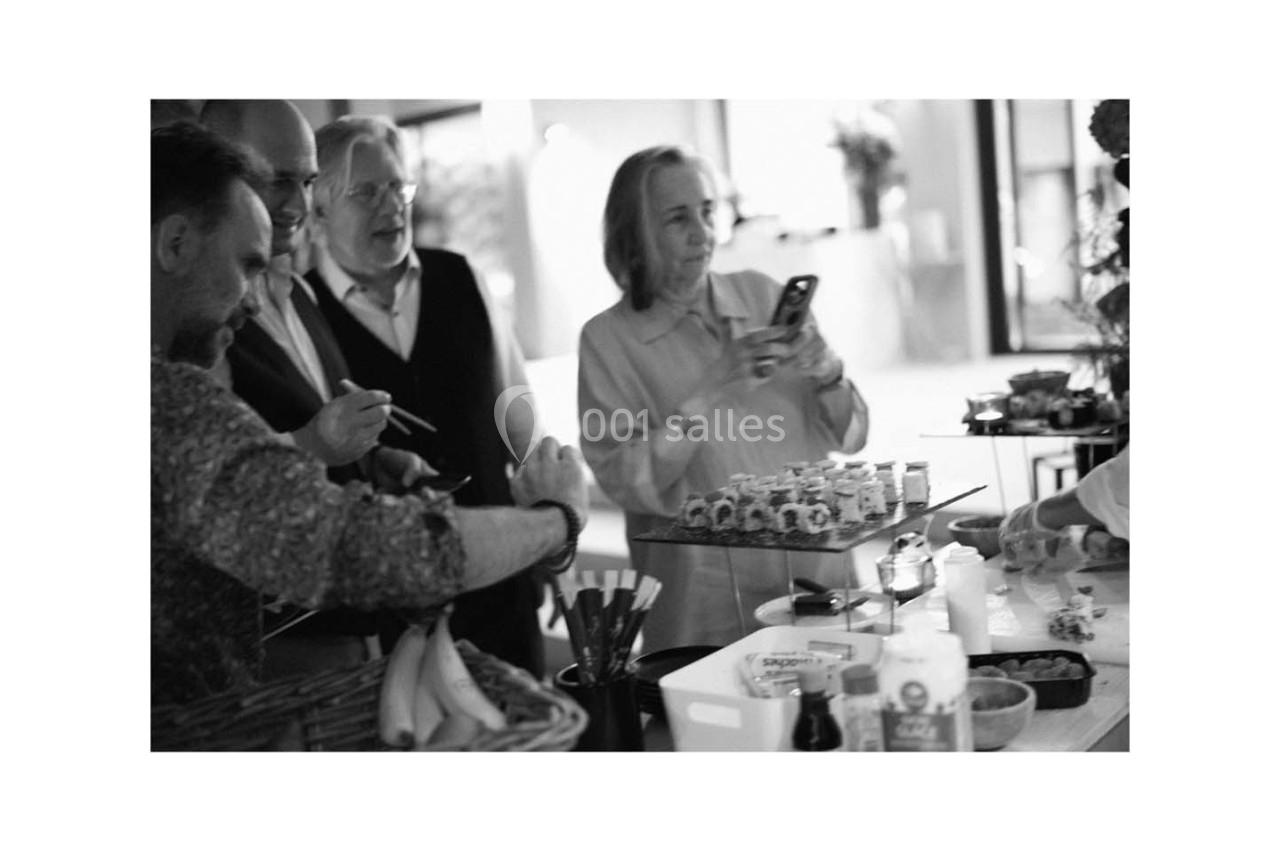 Des personnes rassemblées autour d'une table, observant ou photographiant des plats préparés.
