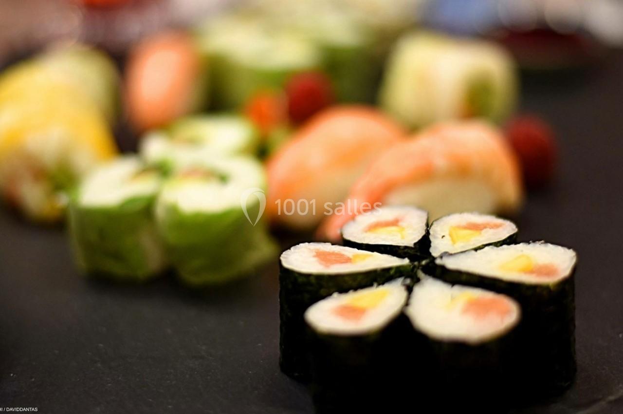 Assortiment de sushis et makis variés disposés sur une assiette sombre.