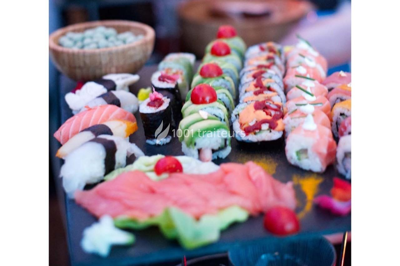 Plateau de sushis variés avec makis, nigiris et sashimis, décorés de tomates cerises et servi sur une ardoise.