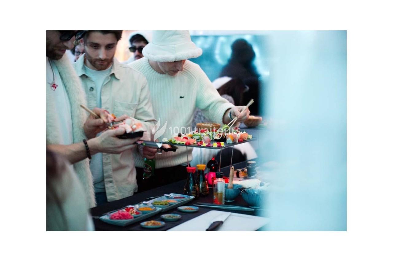Des personnes se servent de sushis et d'accompagnements sur un buffet dans un cadre convivial.