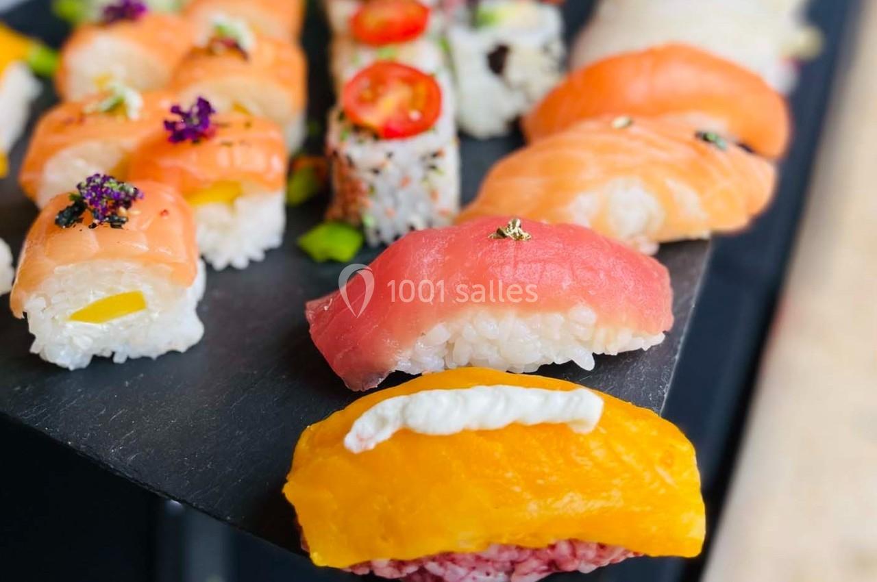 Assortiment de sushis variés présentés sur une ardoise noire, avec des garnitures colorées et fraîches.