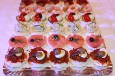 Plateau de canapés variés sur pain blanc, garnis de légumes, herbes fraîches et condiments colorés.