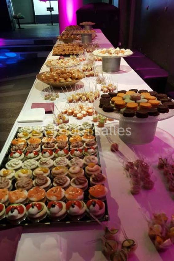 Table garnie de desserts variés, incluant cupcakes, verrines et pâtisseries, disposés pour un buffet.
