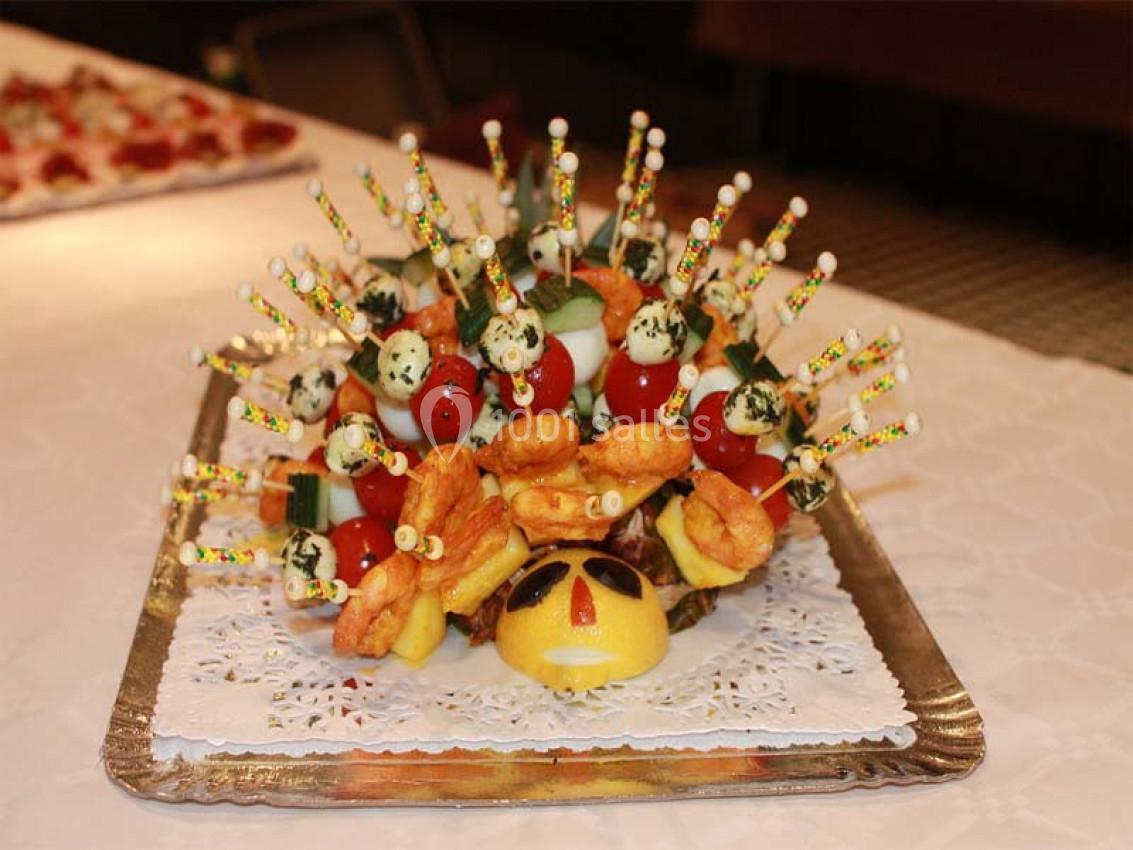 Plateau décoratif avec brochettes de légumes, œufs et crevettes, disposées en hérisson sur une base en fruit.