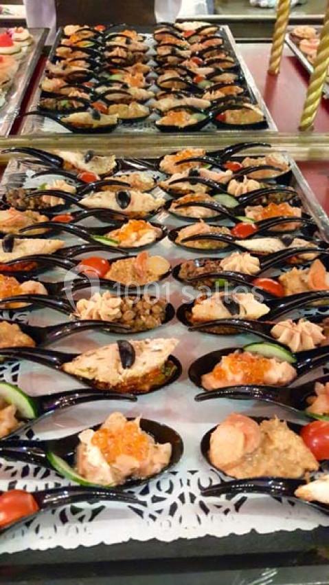 Plateau de moules garnies de diverses préparations, décorées de tomates cerises, olives et herbes.