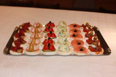 Plateau de canapés variés sur pain blanc, garnis de légumes, herbes fraîches et condiments colorés.