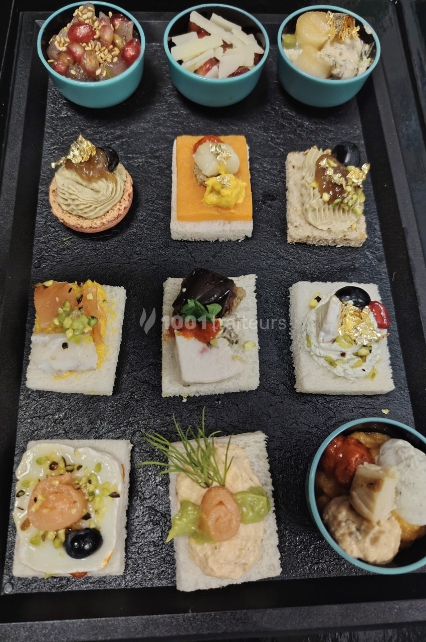 Plateau de canapés variés et colorés accompagnés de petites verrines, présenté sur un plateau noir.