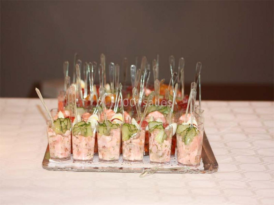 Plateau de verrines variées contenant des ingrédients comme crevettes, concombres et autres garnitures colorées.