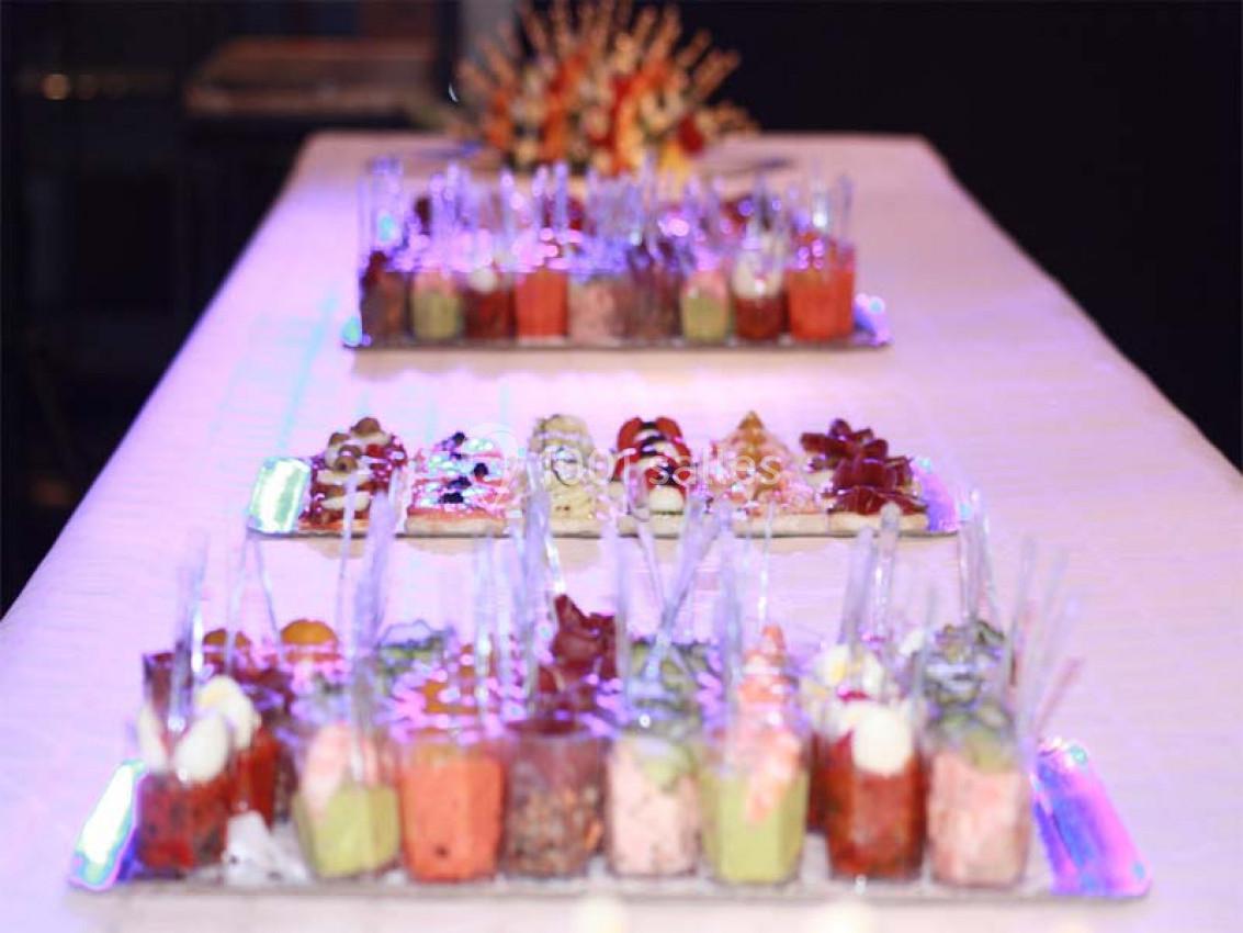 Plateaux de verrines colorées et apéritifs disposés sur une table blanche lors d'un événement.