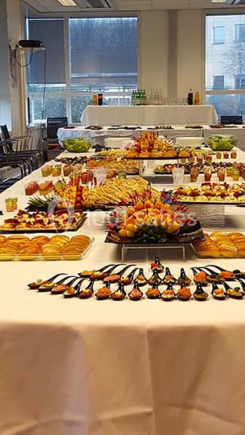 Buffet varié avec plats salés et sucrés disposés sur plusieurs tables dans une salle lumineuse.