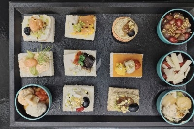 Plateau de canapés variés sur pain blanc, garnis de légumes, herbes fraîches et condiments colorés.