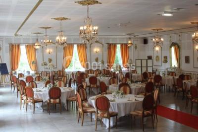 Chambre classique avec lit double, mobilier en bois, rideaux dorés et lumière naturelle entrant par une fenêtre.