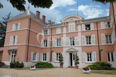 Chambre classique avec lit double, mobilier en bois, rideaux dorés et lumière naturelle entrant par une fenêtre.