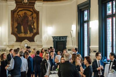 Miniature Traiteur Paris (Paris) - Profumo Traiteur Italien #23 Des personnes discutent en petits groupes lors d'un événement dans une salle élégante avec des vitraux et une fresque murale.