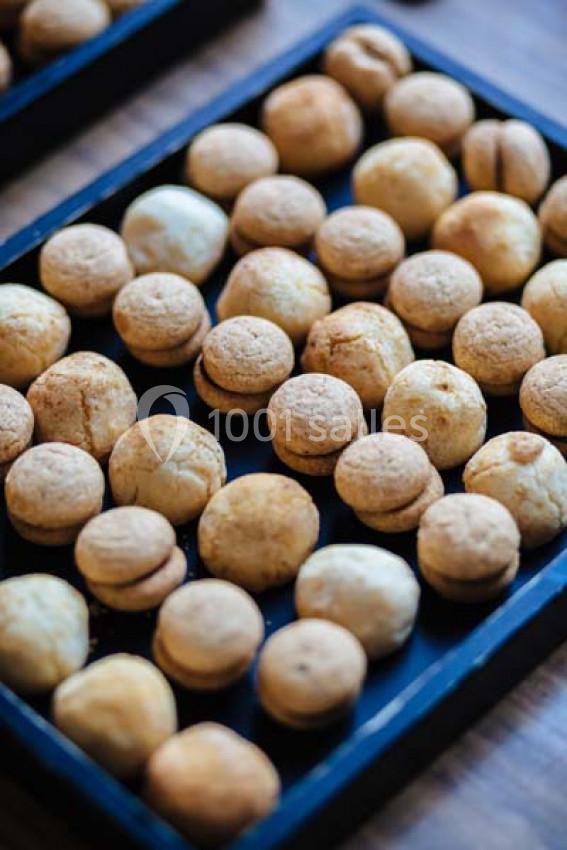 Plateaux remplis de petits biscuits dorés ronds alignés sur une surface sombre.