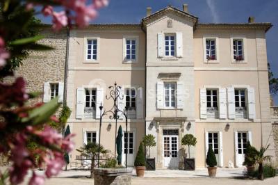 Terrain de tennis entouré d'arbres et de végétation, avec un olivier au premier plan.