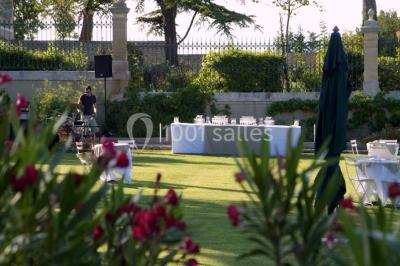 Terrain de tennis entouré d'arbres et de végétation, avec un olivier au premier plan.