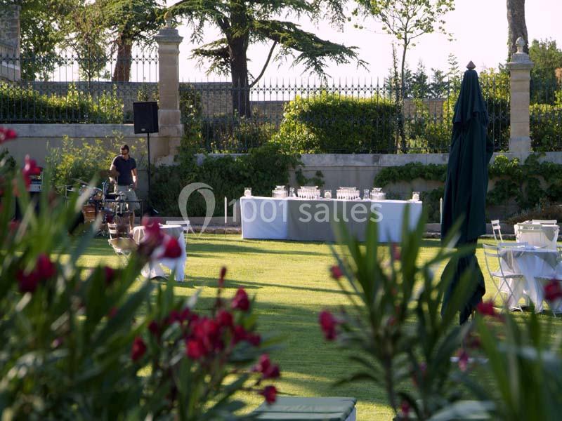Jardin aménagé avec tables, chaises et buffet en arrière-plan, entouré de verdure et de fleurs au premier plan.