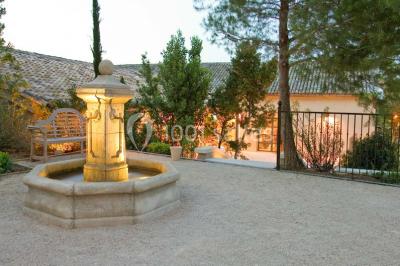 Terrain de tennis entouré d'arbres et de végétation, avec un olivier au premier plan.