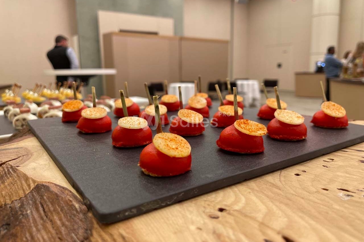 Plateau de bouchées apéritives composées de tomates cerises et rondelles de fromage, présentées sur une ardoise.