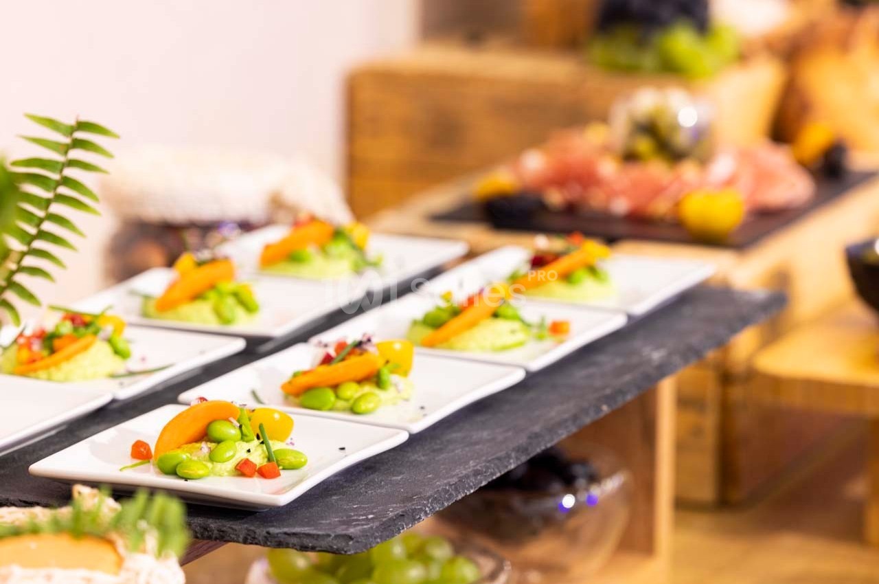 Assiettes individuelles garnies de légumes frais et colorés, disposées sur une table en ardoise dans un buffet.