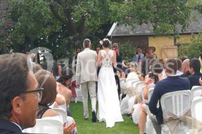 Banc en bois sous une arche décorée de feuilles d'automne, entouré de bougies et de feuilles au sol dans une salle rustique.