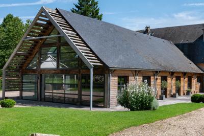 Banc en bois sous une arche décorée de feuilles d'automne, entouré de bougies et de feuilles au sol dans une salle rustique.