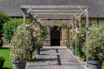 Banc en bois sous une arche décorée de feuilles d'automne, entouré de bougies et de feuilles au sol dans une salle rustique.