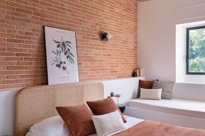 Banc en bois sous une arche décorée de feuilles d'automne, entouré de bougies et de feuilles au sol dans une salle rustique.