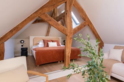 Banc en bois sous une arche décorée de feuilles d'automne, entouré de bougies et de feuilles au sol dans une salle rustique.