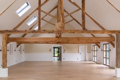 Banc en bois sous une arche décorée de feuilles d'automne, entouré de bougies et de feuilles au sol dans une salle rustique.