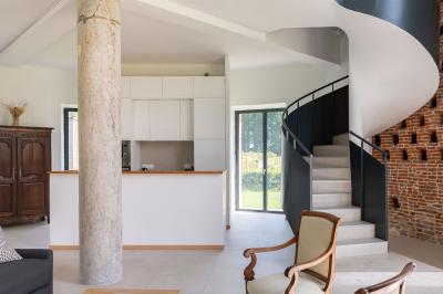 Banc en bois sous une arche décorée de feuilles d'automne, entouré de bougies et de feuilles au sol dans une salle rustique.