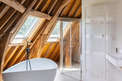 Banc en bois sous une arche décorée de feuilles d'automne, entouré de bougies et de feuilles au sol dans une salle rustique.