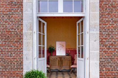 Banc en bois sous une arche décorée de feuilles d'automne, entouré de bougies et de feuilles au sol dans une salle rustique.