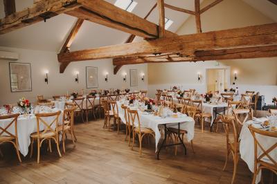 Banc en bois sous une arche décorée de feuilles d'automne, entouré de bougies et de feuilles au sol dans une salle rustique.