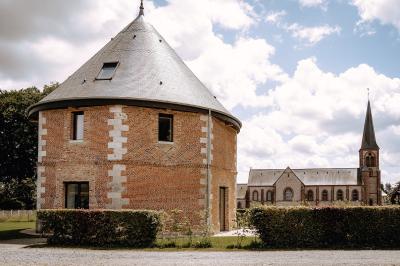 Banc en bois sous une arche décorée de feuilles d'automne, entouré de bougies et de feuilles au sol dans une salle rustique.