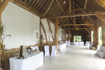 Banc en bois sous une arche décorée de feuilles d'automne, entouré de bougies et de feuilles au sol dans une salle rustique.