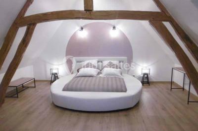 Miniature Location salle Argueil (Seine-Maritime) - Domaine de Clairval #26 Lit double avec tête de lit sombre, draps gris et blancs, encadré par deux tables de chevet avec lampes, dans une chambre…