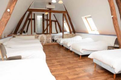 Miniature Location salle Argueil (Seine-Maritime) - Domaine de Clairval #28 Lit double avec tête de lit sombre, draps gris et blancs, encadré par deux tables de chevet avec lampes, dans une chambre…