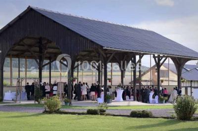 Miniature Location salle Argueil (Seine-Maritime) - Domaine de Clairval #20 Lit double avec tête de lit sombre, draps gris et blancs, encadré par deux tables de chevet avec lampes, dans une chambre…