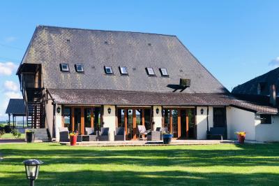 Miniature Location salle Argueil (Seine-Maritime) - Domaine de Clairval #9 Lit double avec tête de lit sombre, draps gris et blancs, encadré par deux tables de chevet avec lampes, dans une chambre…