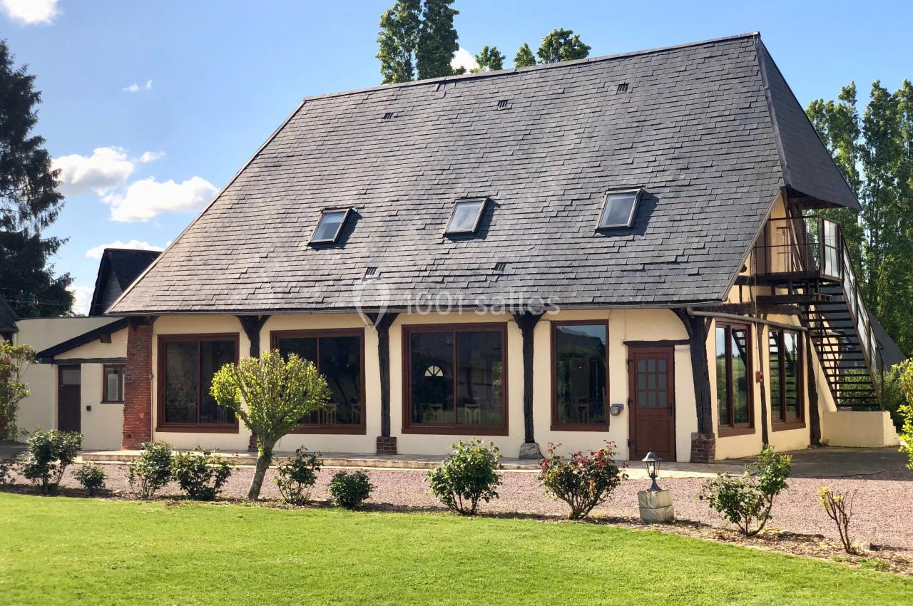 Location salle Argueil (Seine-Maritime) - Domaine de Clairval #8 Maison à colombages avec toit en ardoise, fenêtres mansardées et jardin arboré sous un ciel dégagé.