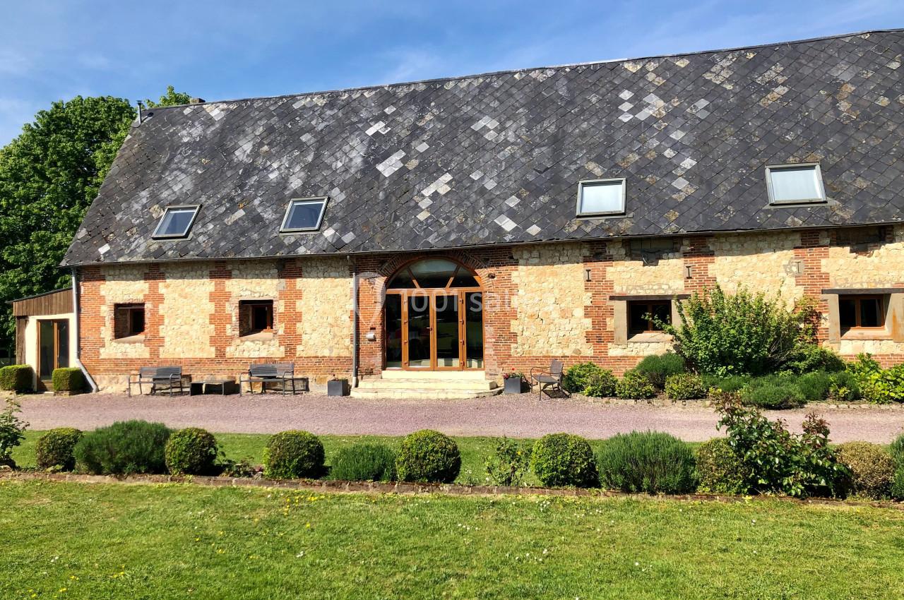 Location salle Argueil (Seine-Maritime) - Domaine de Clairval #12 Façade d'une grande maison en briques et pierres avec toit en ardoise, entourée de pelouse et d'arbustes.