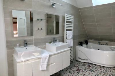 Miniature Location salle Argueil (Seine-Maritime) - Domaine de Clairval #27 Lit double avec tête de lit sombre, draps gris et blancs, encadré par deux tables de chevet avec lampes, dans une chambre…