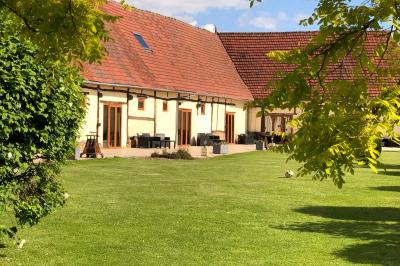 Miniature Location salle Argueil (Seine-Maritime) - Domaine de Clairval #14 Lit double avec tête de lit sombre, draps gris et blancs, encadré par deux tables de chevet avec lampes, dans une chambre…